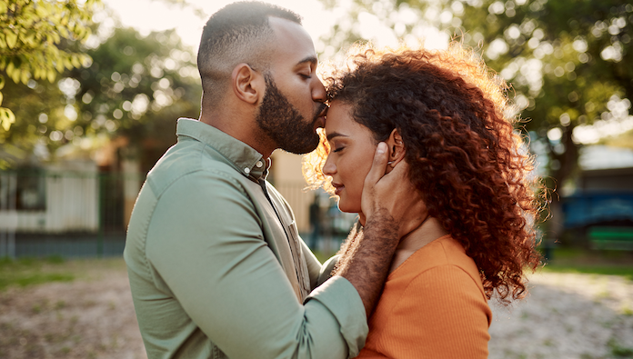 Man kissing woman's head